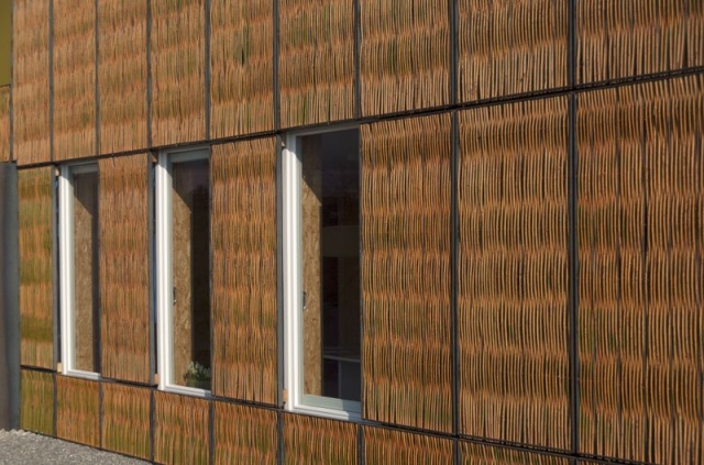 eine Hausfassade ist vollständig mit Weidenruten bedeckt, nur die Fenster sind frei