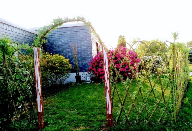 Umzäunung eines Grundstückes mit einem Weidenrautenzaun, im Torbereich ein Weidenbogen